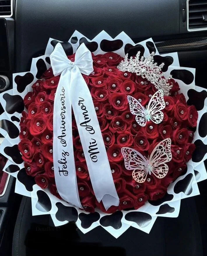 A red floral arrangement with pale ribbons, butterfly decorations, and dark wrapping.