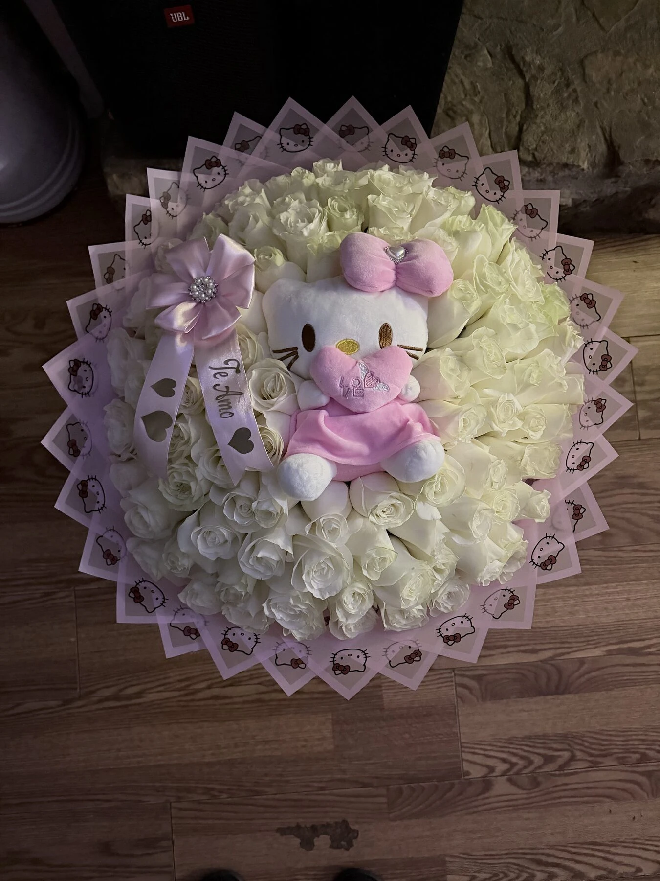 A pale floral arrangement with a small pink plush toy at the center.