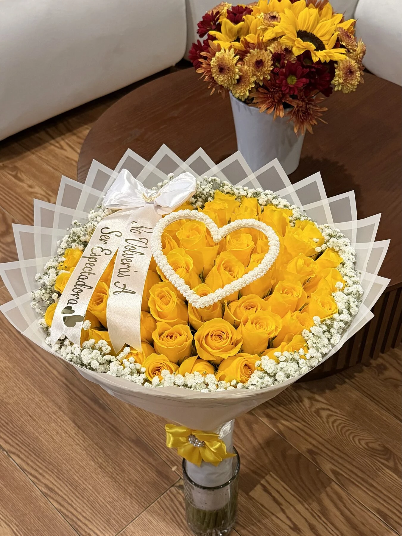 A yellow floral arrangement with a white heart detail, photographed from above.