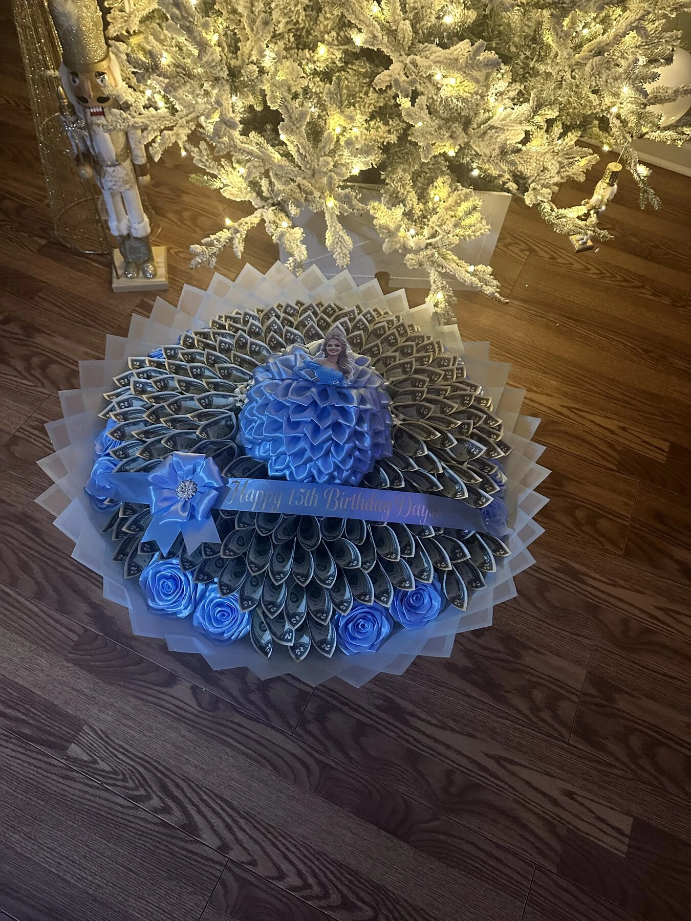 A blue round arrangement made from folded bills, photographed on a dark floor.