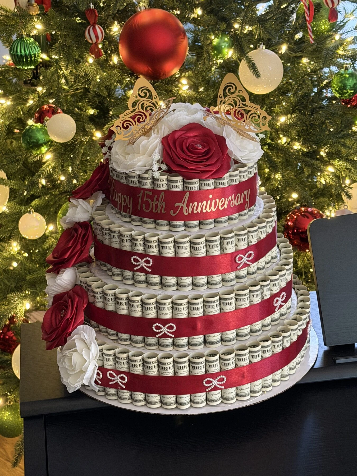 A tiered red and cream arrangement photographed beside a decorated tree.