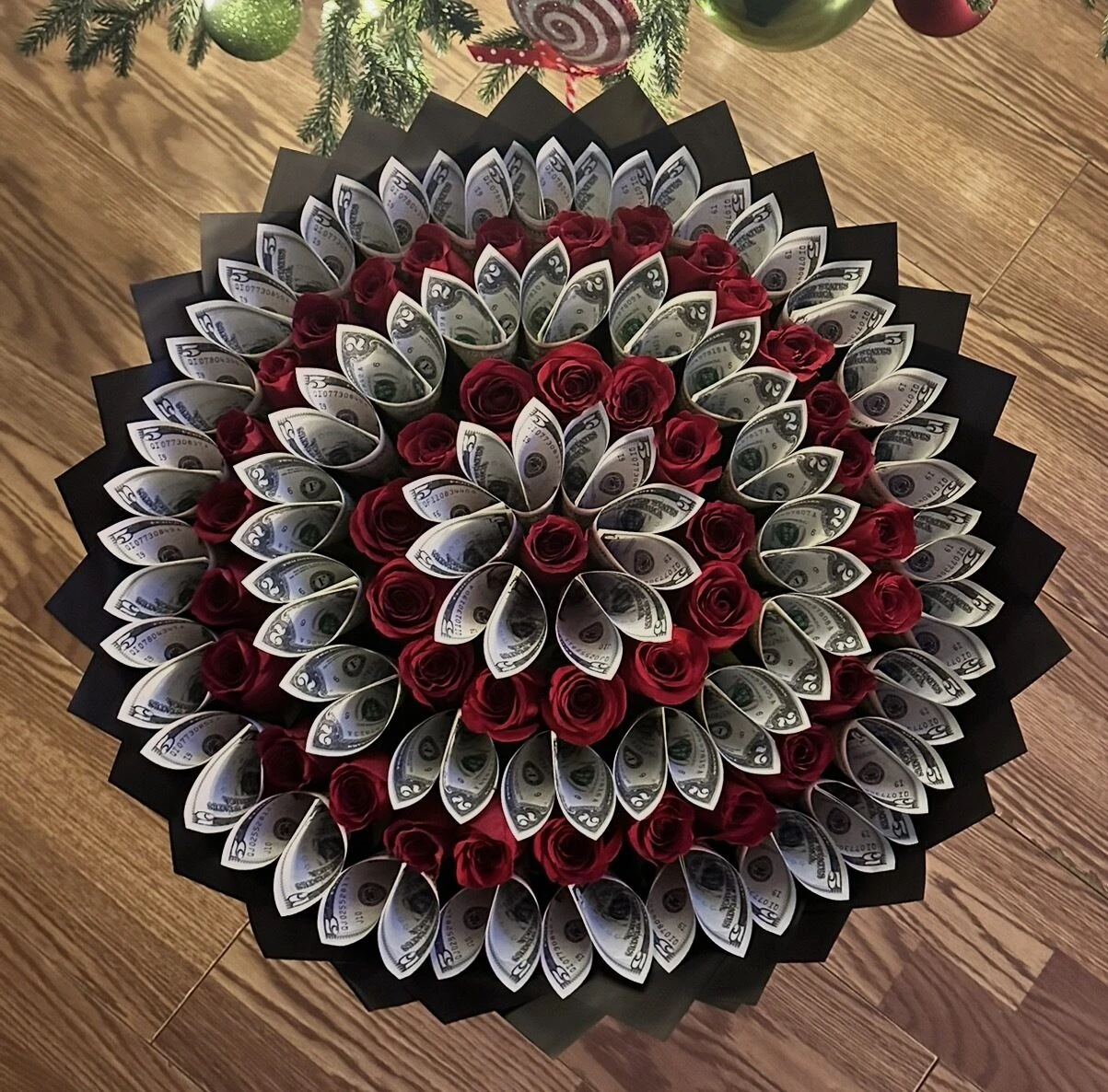 A round arrangement of folded bills with a red and white floral center.