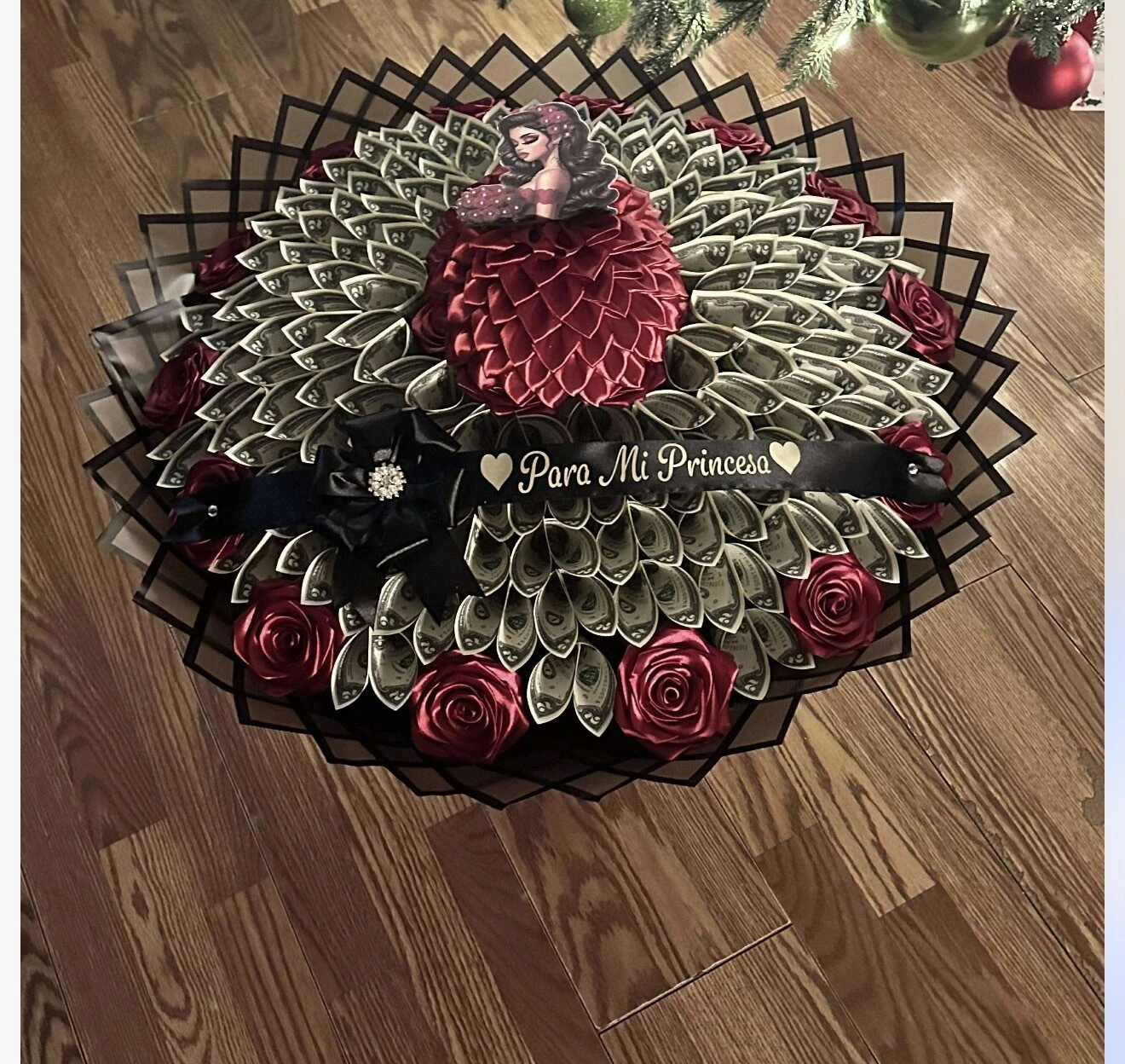 A round arrangement of folded bills around a red center with dark wrapping.