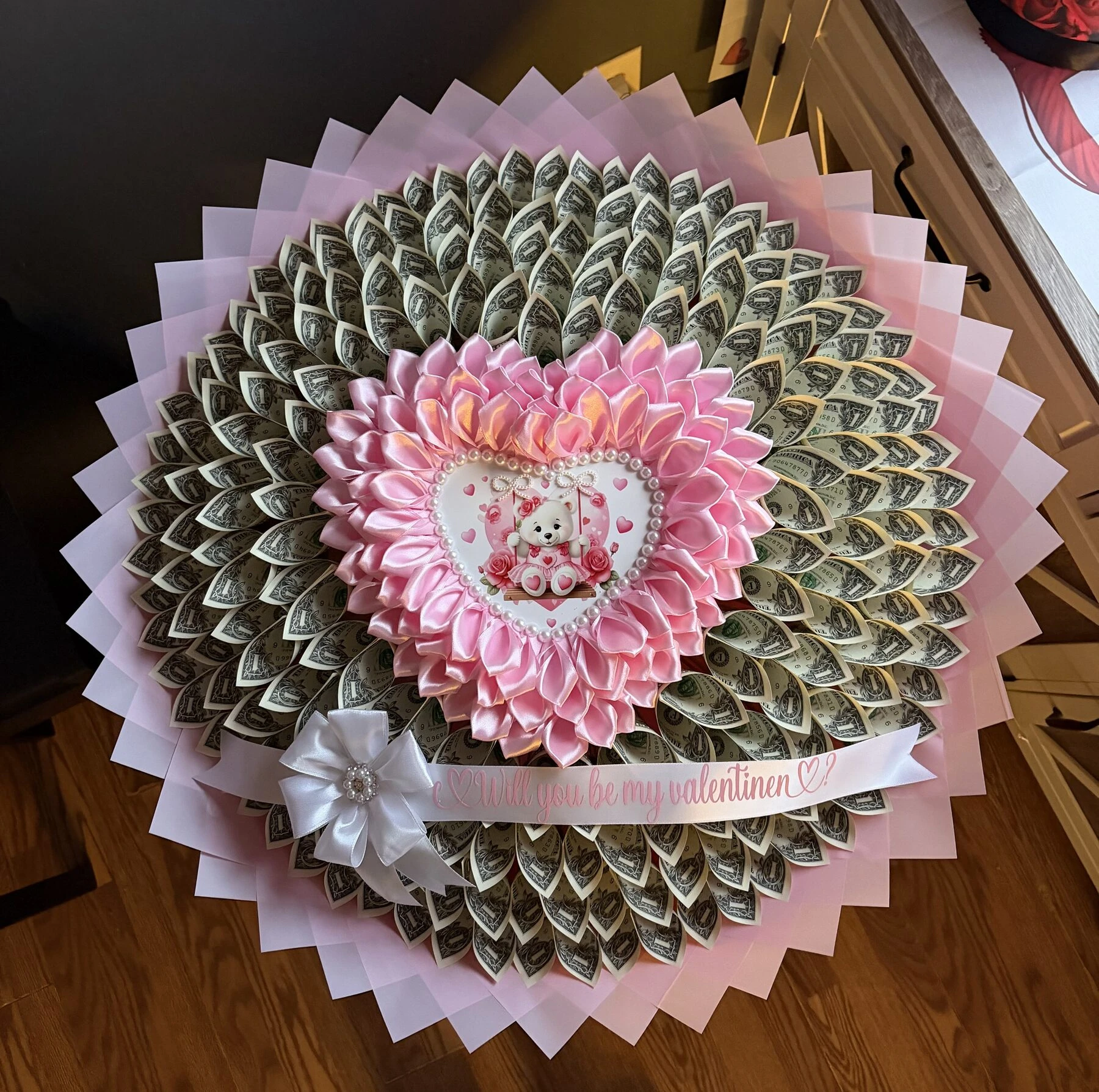 A pink heart-shaped arrangement with layered pale wrapping and a small center detail.