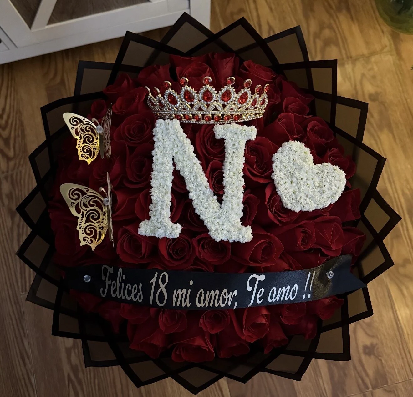 A red and black floral arrangement with a large white letter and heart detail.