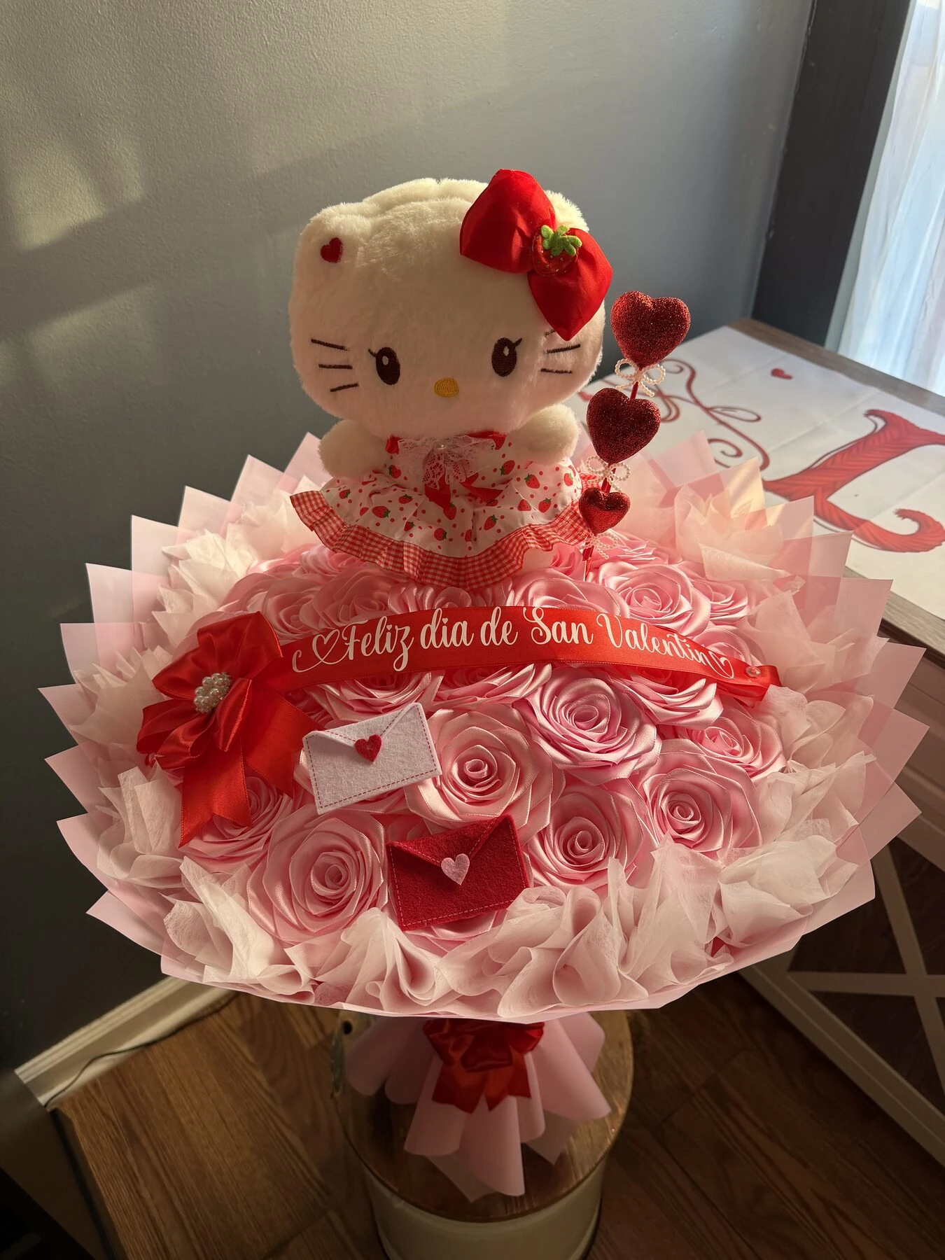 A pink floral arrangement with a small plush character and pale wrapping.