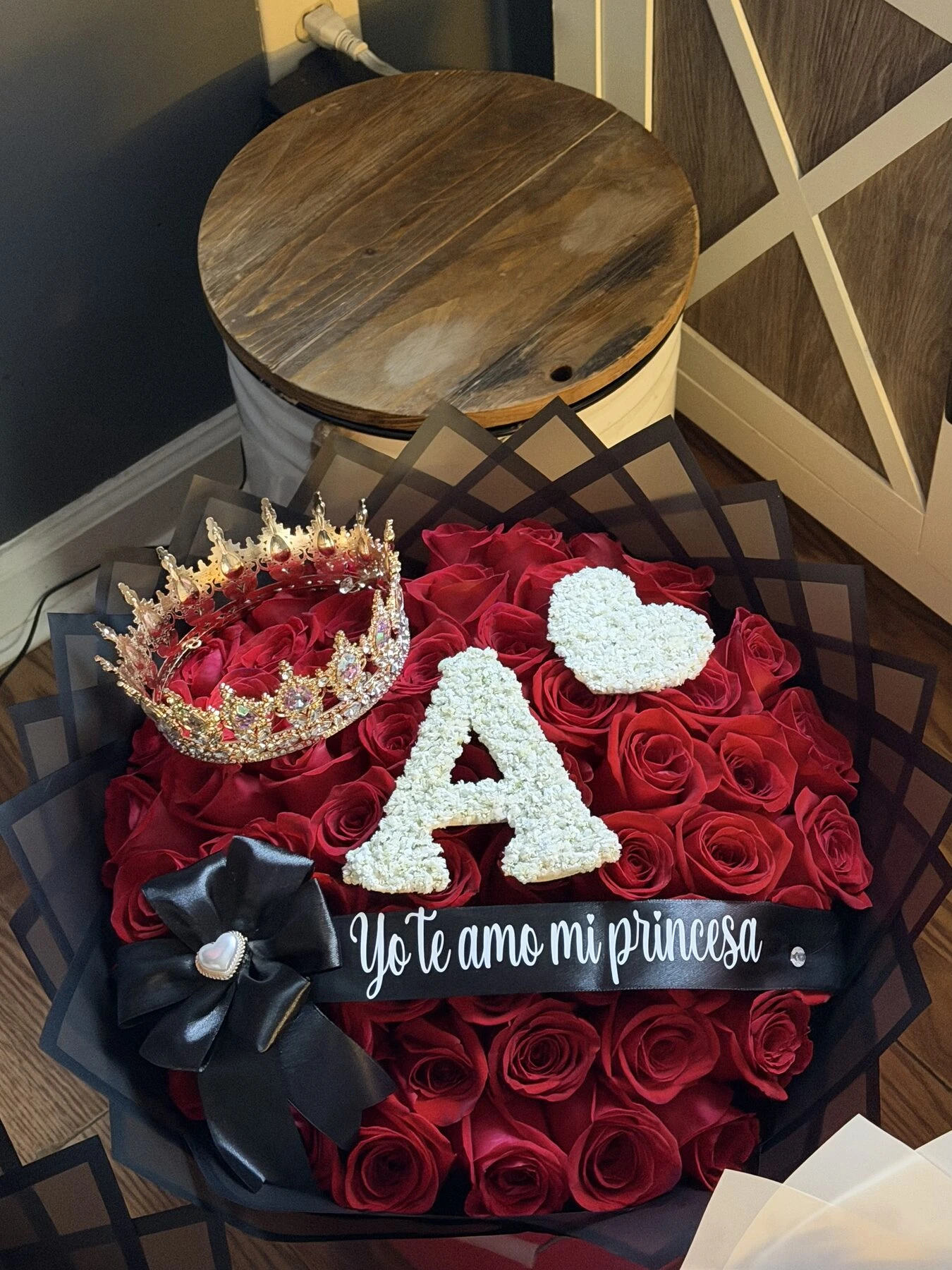 A red floral arrangement with a large pale letter and a dark ribbon.