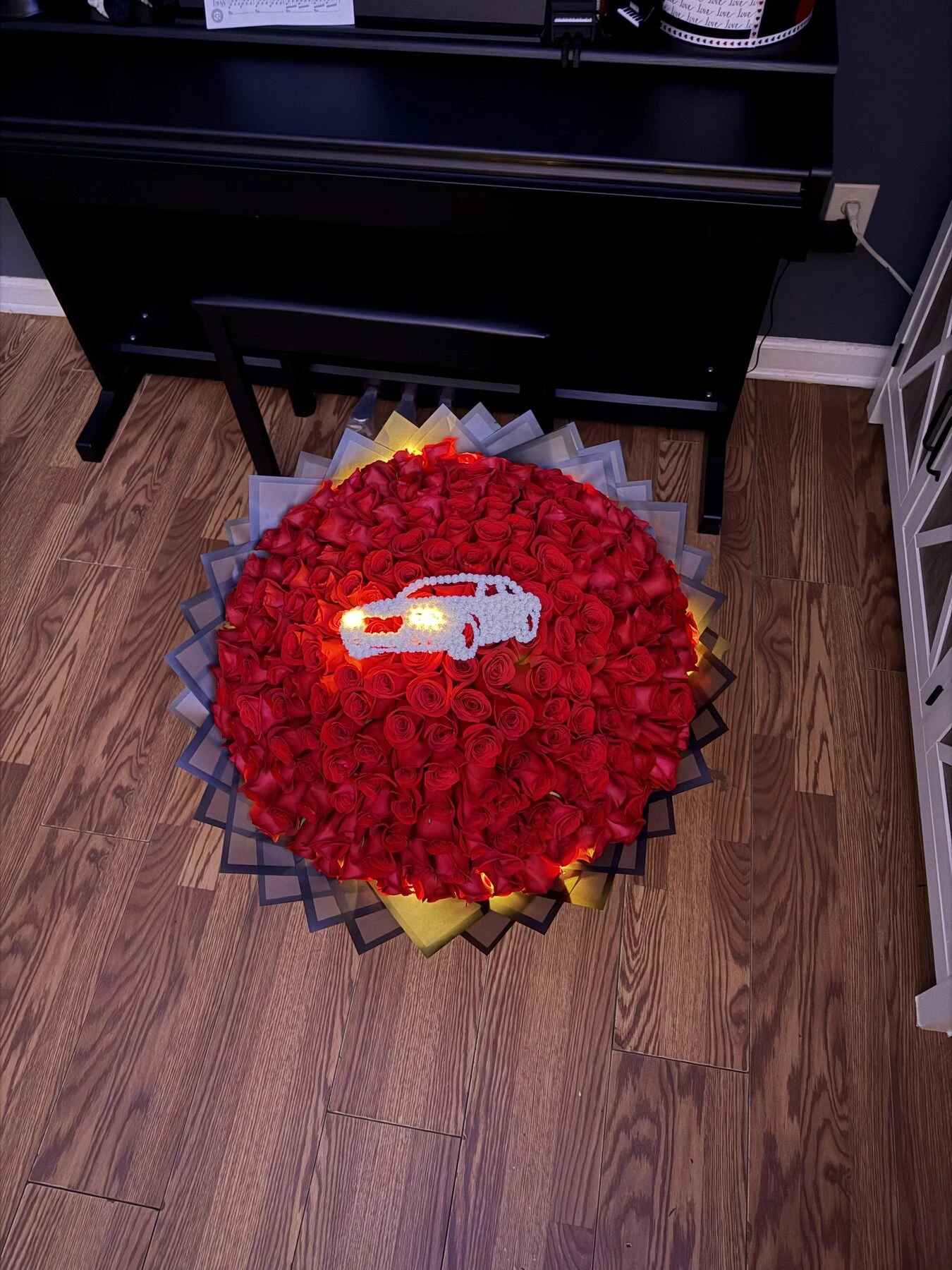 A round red arrangement with dark wrapping, photographed from above.