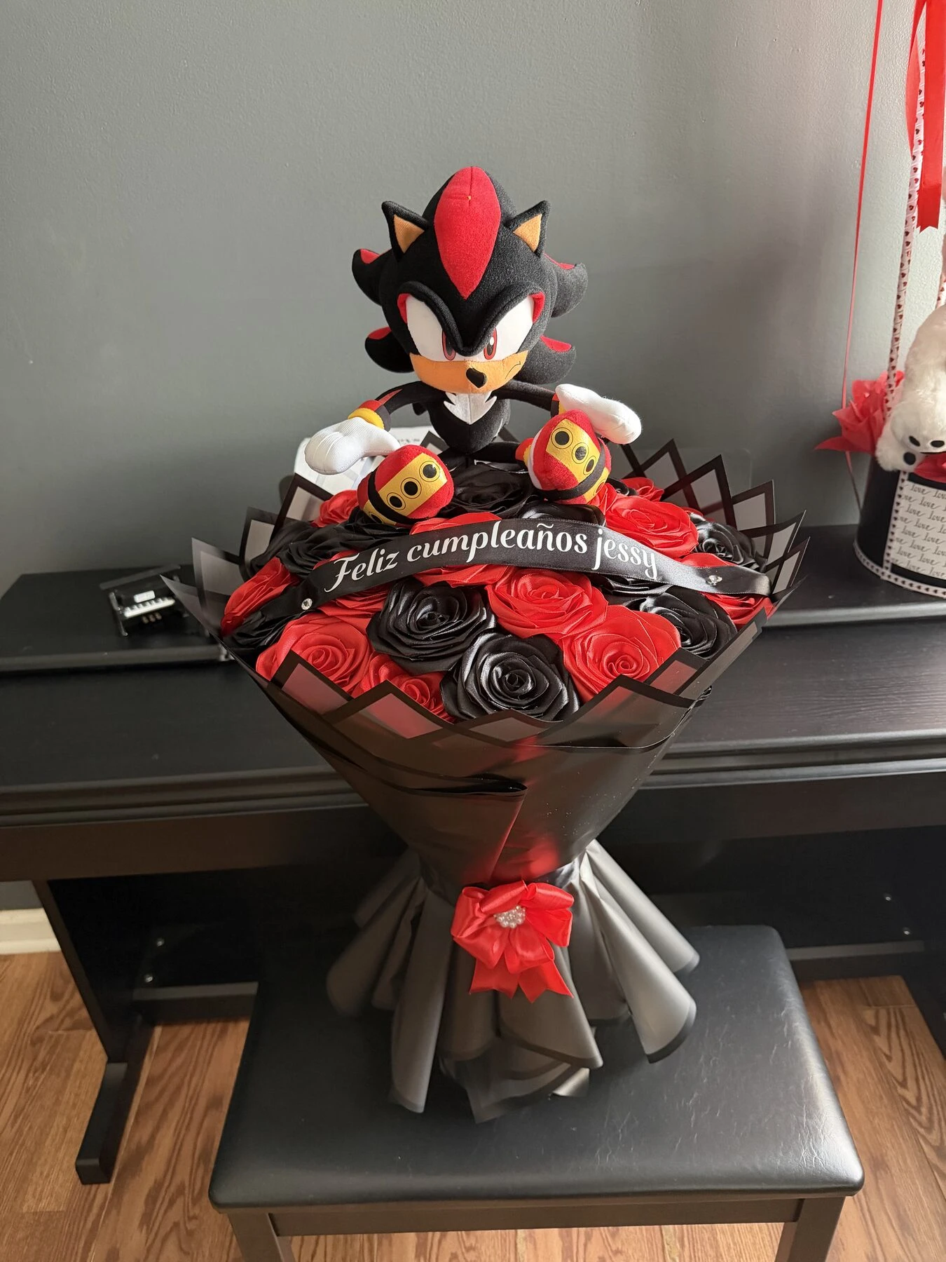 A red and black wrapped bouquet with a plush character standing at the center.