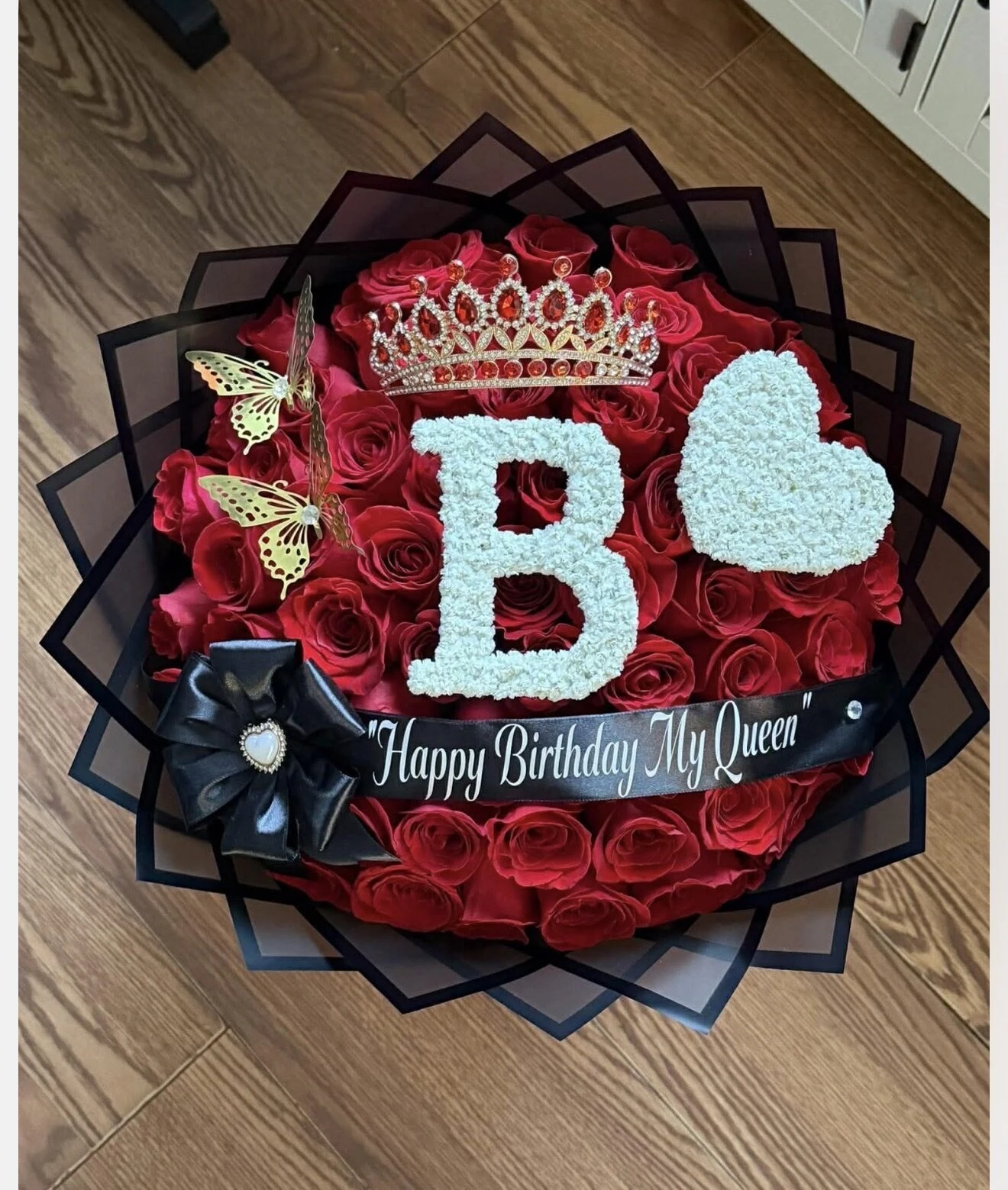 A round red arrangement with folded bills and a large pale letter in the center.