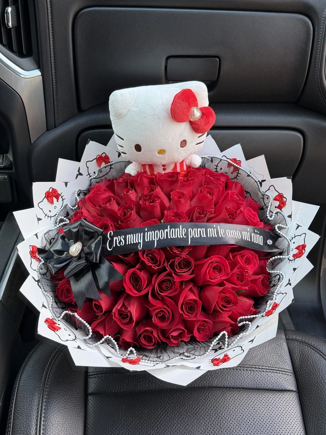 A red floral arrangement with a white plush character, dark bow, and printed wrapping.