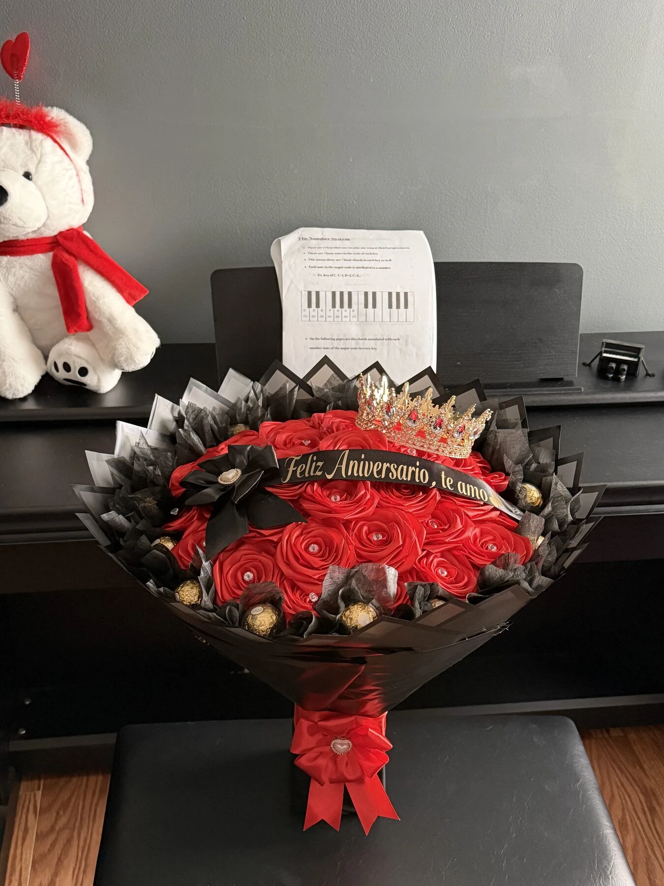A small red arrangement displayed in a vase with a ribbon and a message band.