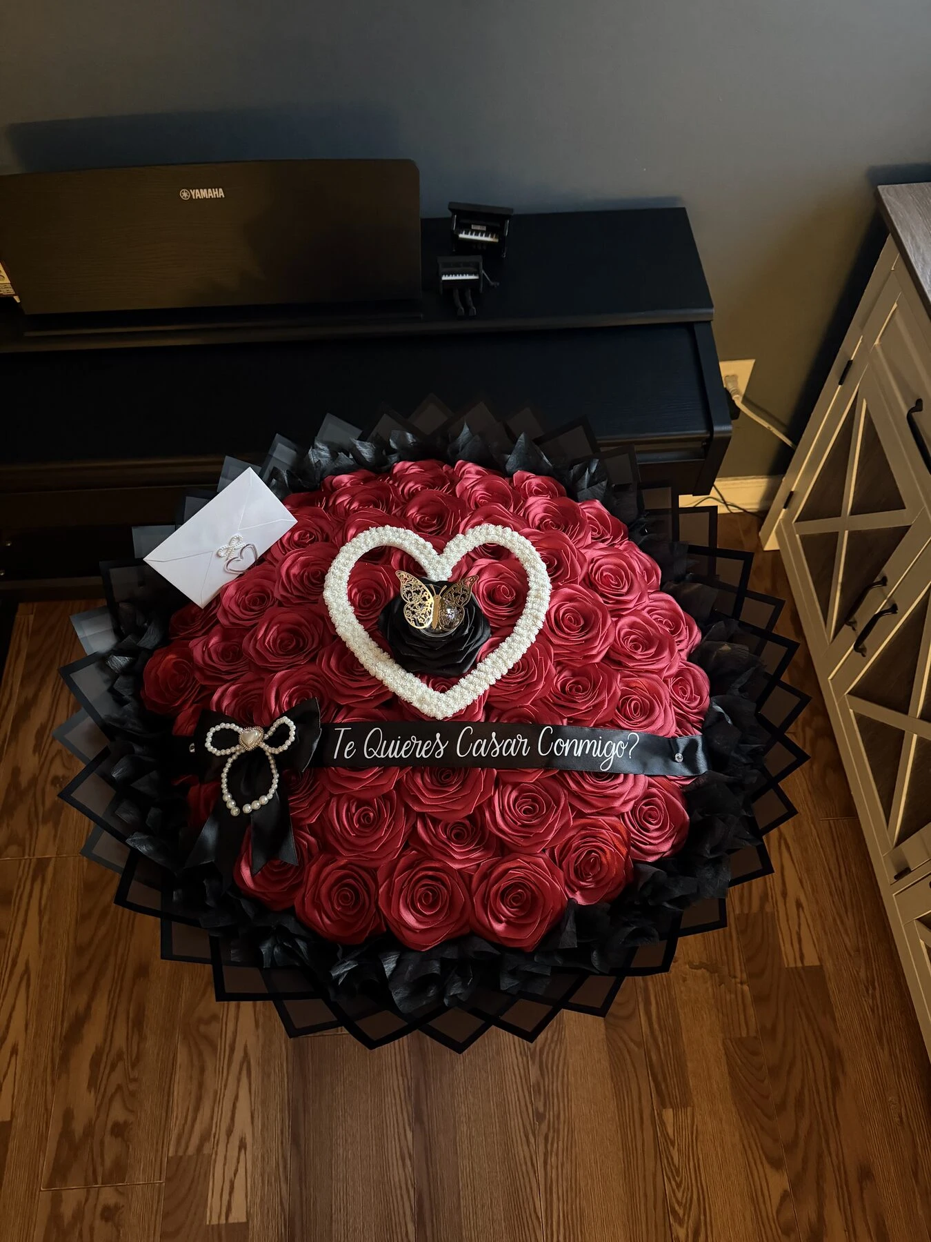 A dark red floral arrangement with a heart detail and small decorative accents.