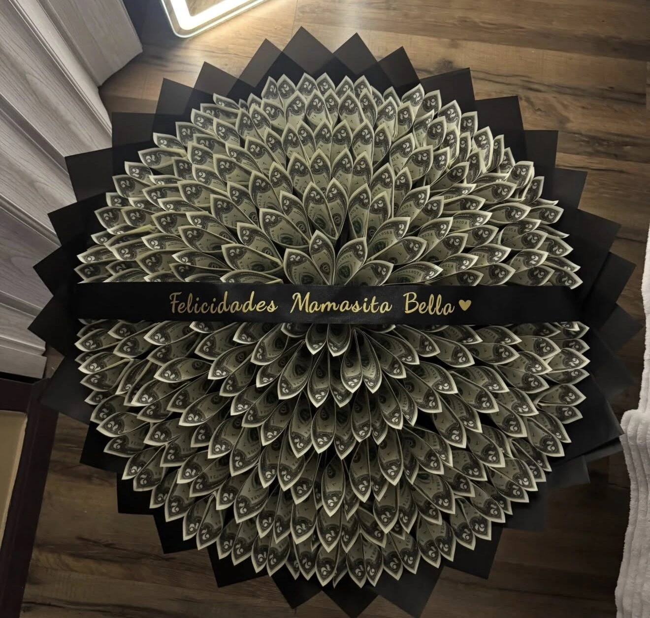 A large circular arrangement made from folded bills with a dark band across the center.