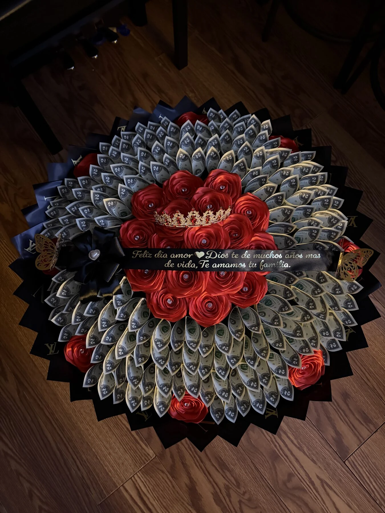 A red round arrangement with folded bills and dark layered wrapping.