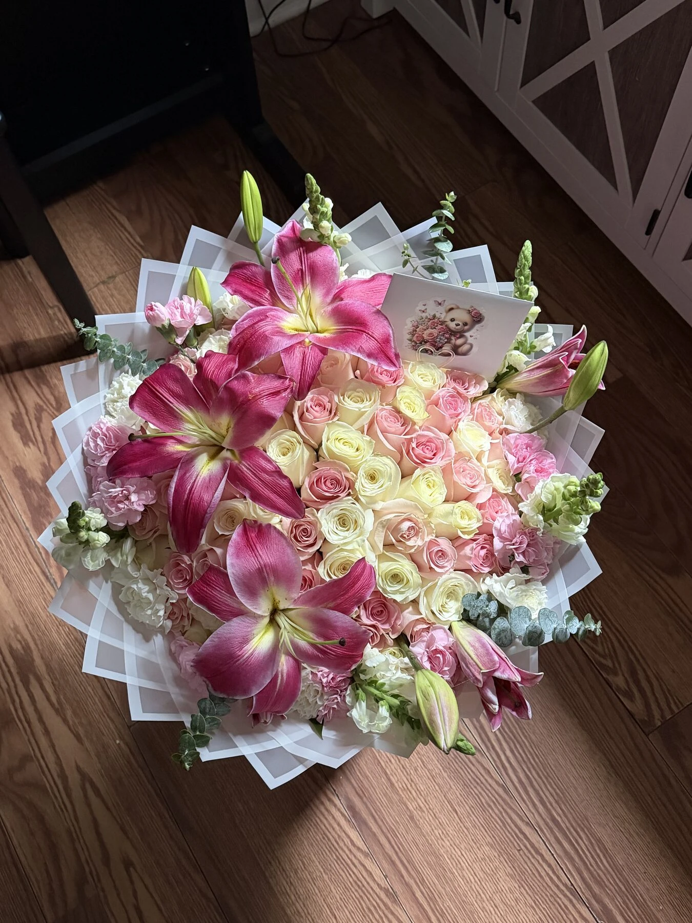 Large pink blooms and smaller white and pale pink flowers with greenery in light wrapping.
